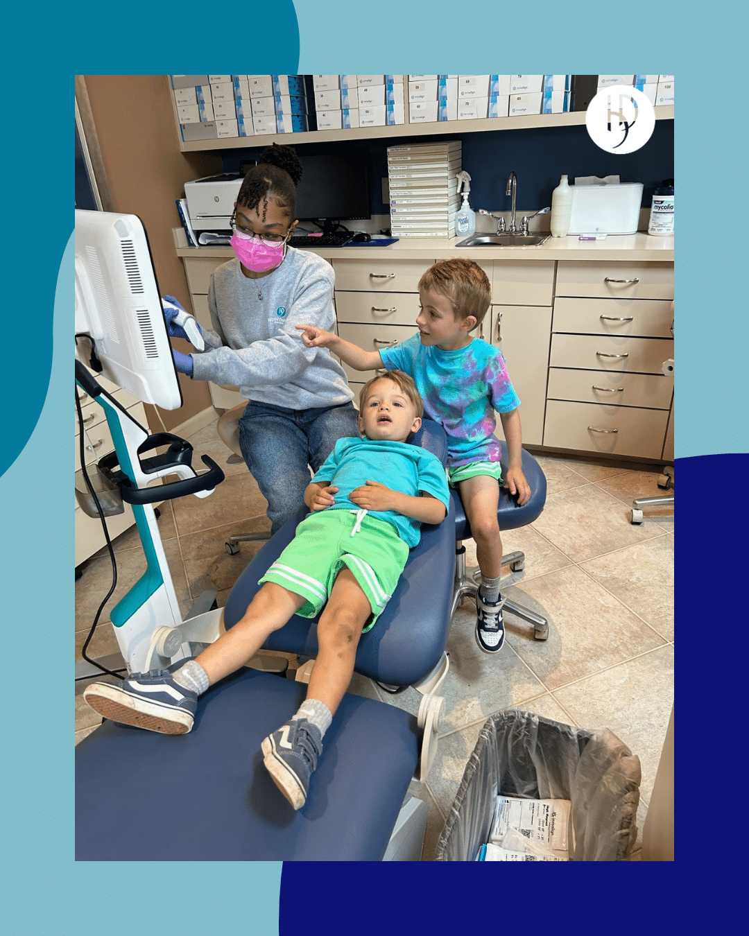 An orthodontic assistant shows two young boys their digital dental scans on a clinic monitor.