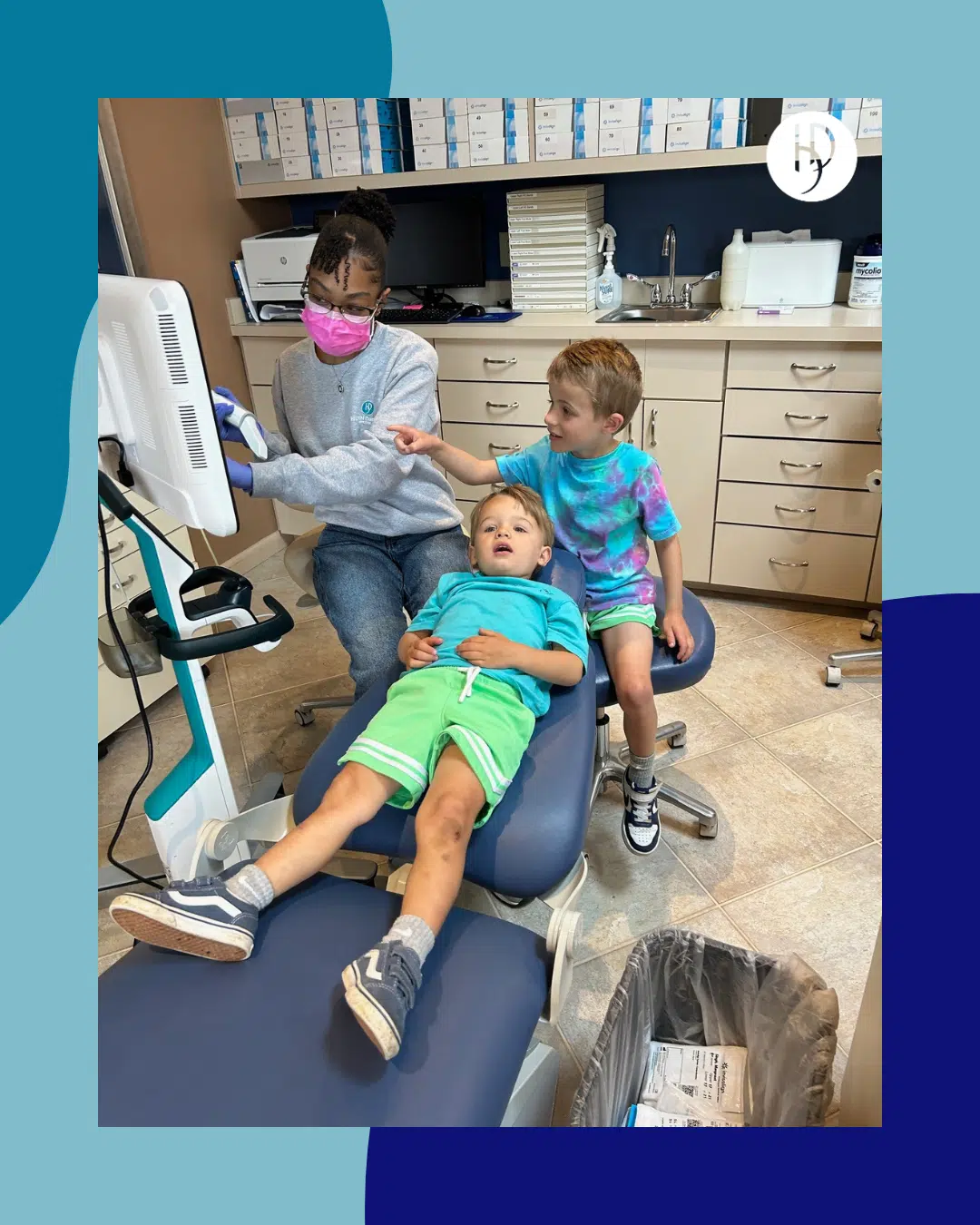 An orthodontic assistant shows two young boys their digital dental scans on a clinic monitor.